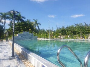 Una piscina cristalina con una pared de piedra y palmeras al fondo.