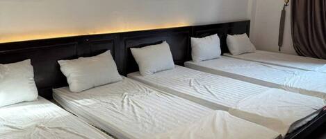 A hotel room with a large bed, a headboard, and two paintings on the wall.