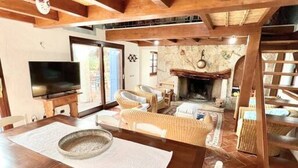 A cozy living room with a fireplace, wicker furniture, and a television. - Li Funnesi Villa sleeps 4, 2 bathrooms, A.C and large garden in San Teodoro (San Teodoro)