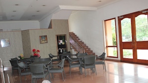 Un comedor amplio con una escalera que lleva a un nivel superior, un ventanal con vistas a vegetación y un televisor montado en la pared.
