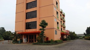 Un edificio de varios pisos con un toldo rojo, un pequeño árbol en la parte delantera y un patio empedrado.