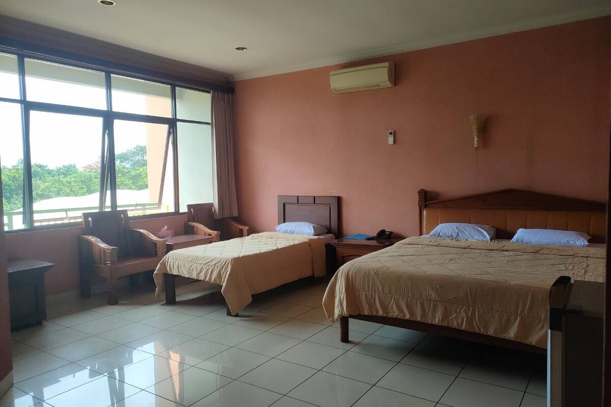 A hotel room with two beds, a desk, a chair, and a window with curtains.
