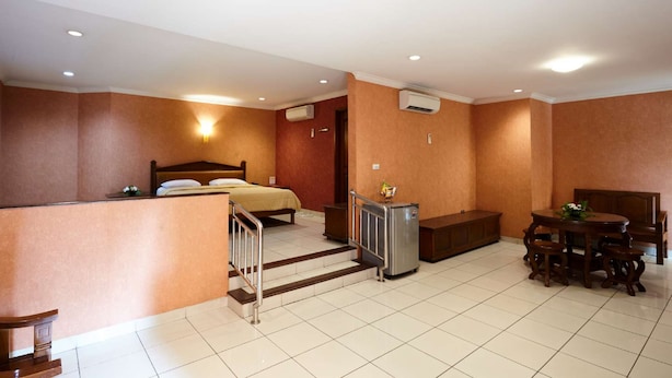 Una habitación de hotel con cama, escritorio, silla, refrigerador pequeño y mesa de comedor con sillas.