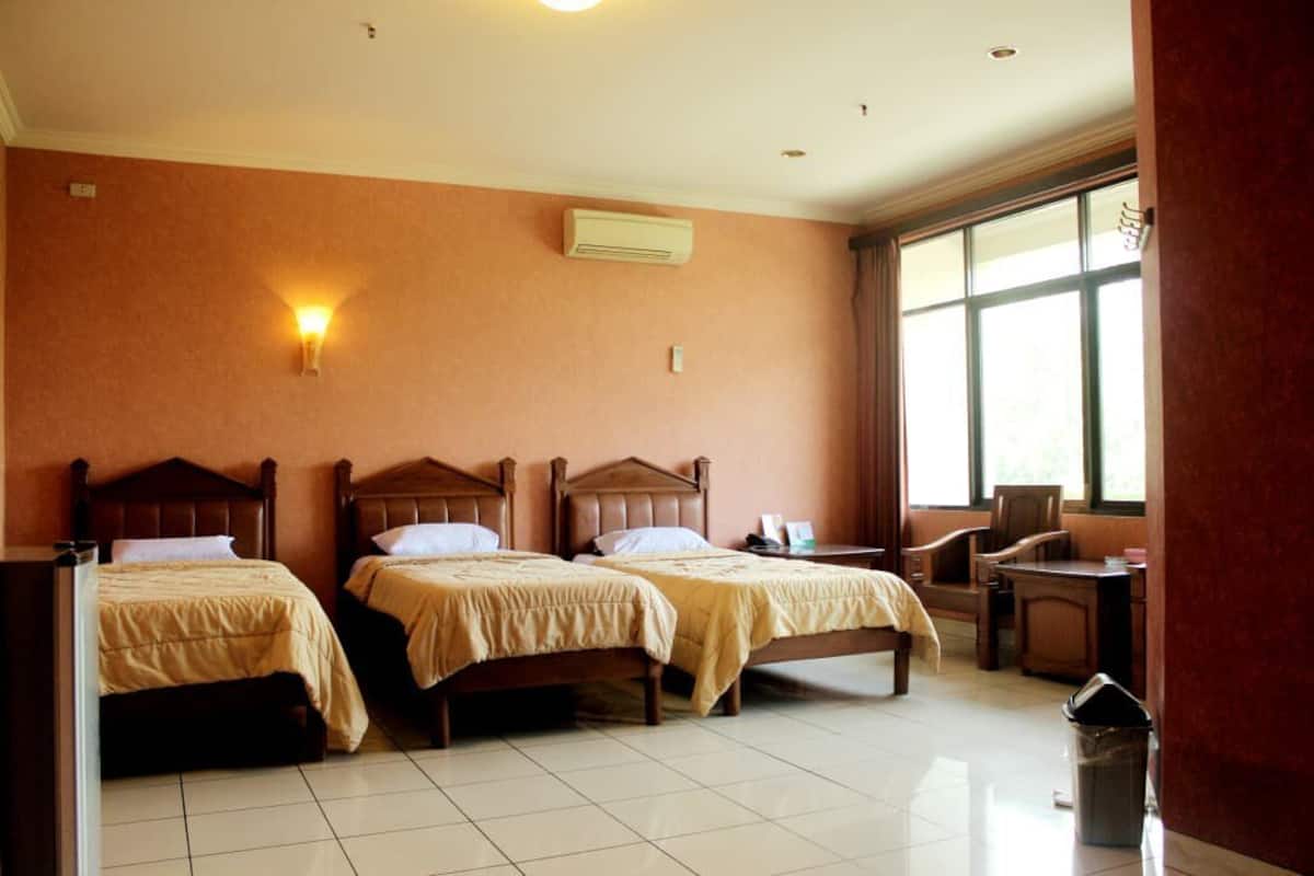 A hotel room with two wooden beds, a desk, a chair, a trash bin, and a window with curtains.