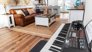 Ein Wohnzimmer mit einem Klavier, einem braunen Ledersofa, einem weißen Couchtisch und einem Teppich.