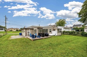 A single-story house with a deck, a small outdoor seating area, and a fenced yard.