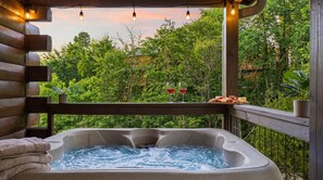 Un jacuzzi con terraza de madera y vista a vegetación exuberante.
