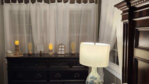 Un aparador de madera oscura con varios cajones, una lámpara blanca con base azul y objetos decorativos encima.
