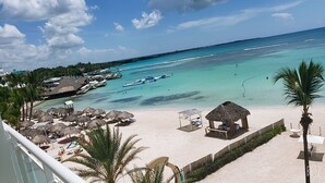 Un complexe hôtelier de bord de mer avec des bungalows aux toits de chaume, des chaises longues et une vue imprenable sur la mer turquoise.