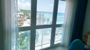 Une chambre dotée d’une grande fenêtre donnant sur une plage et une zone de villégiature.