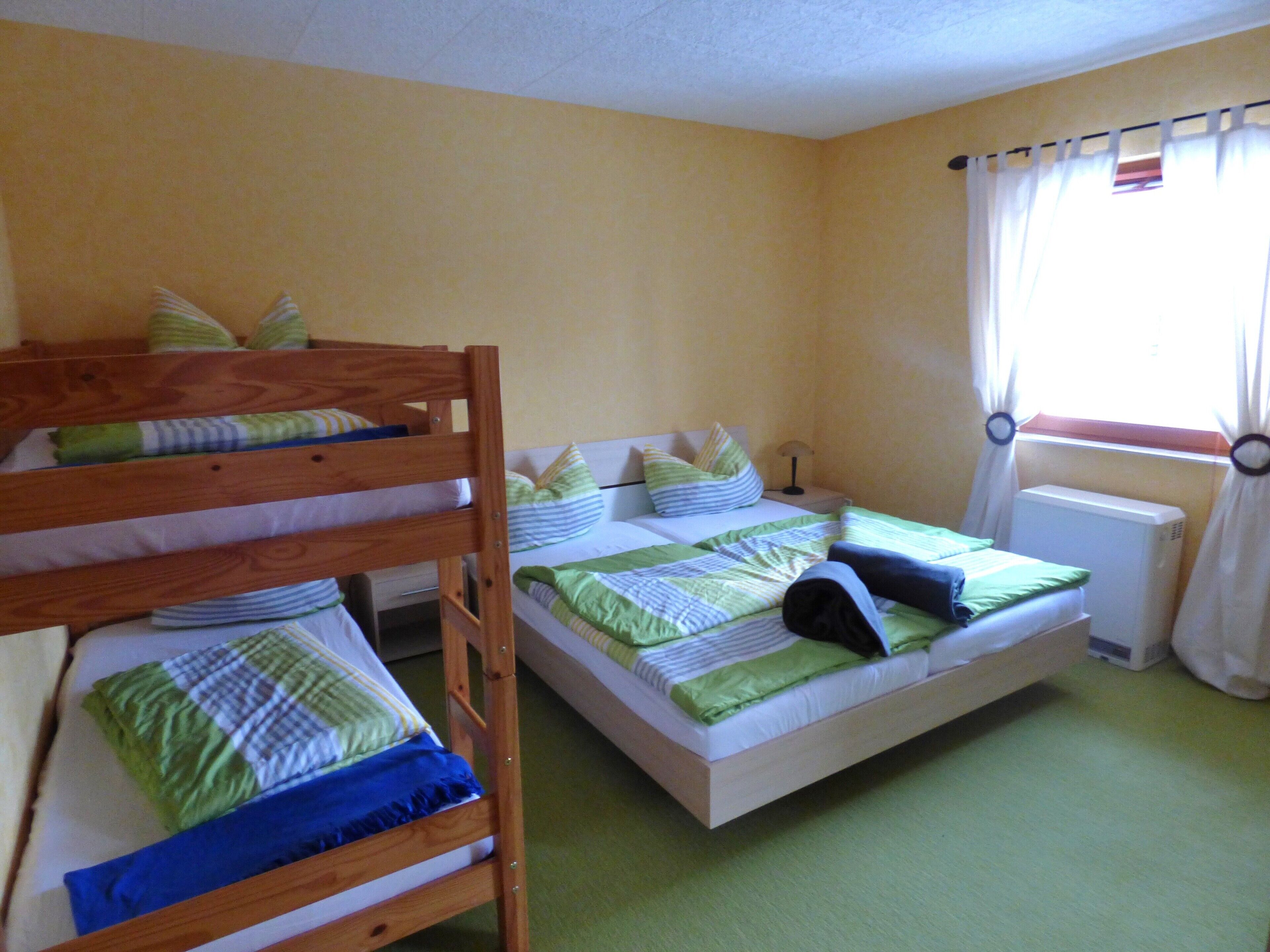Ein Zimmer mit Etagenbetten, einer Heizung und einem fenster mit Vorhängen.