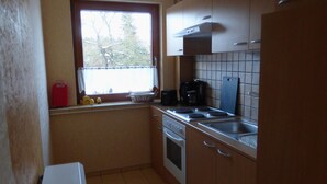 Une cuisine avec une fenêtre, une cuisinière, un évier et un réfrigérateur.