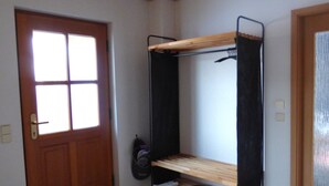 Une pièce avec une porte en bois, une fenêtre, un lit superposé, un tapis noir et un luminaire au plafond.