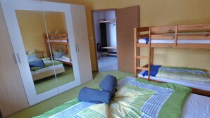 Une chambre avec des lits superposés, une armoire et un miroir.