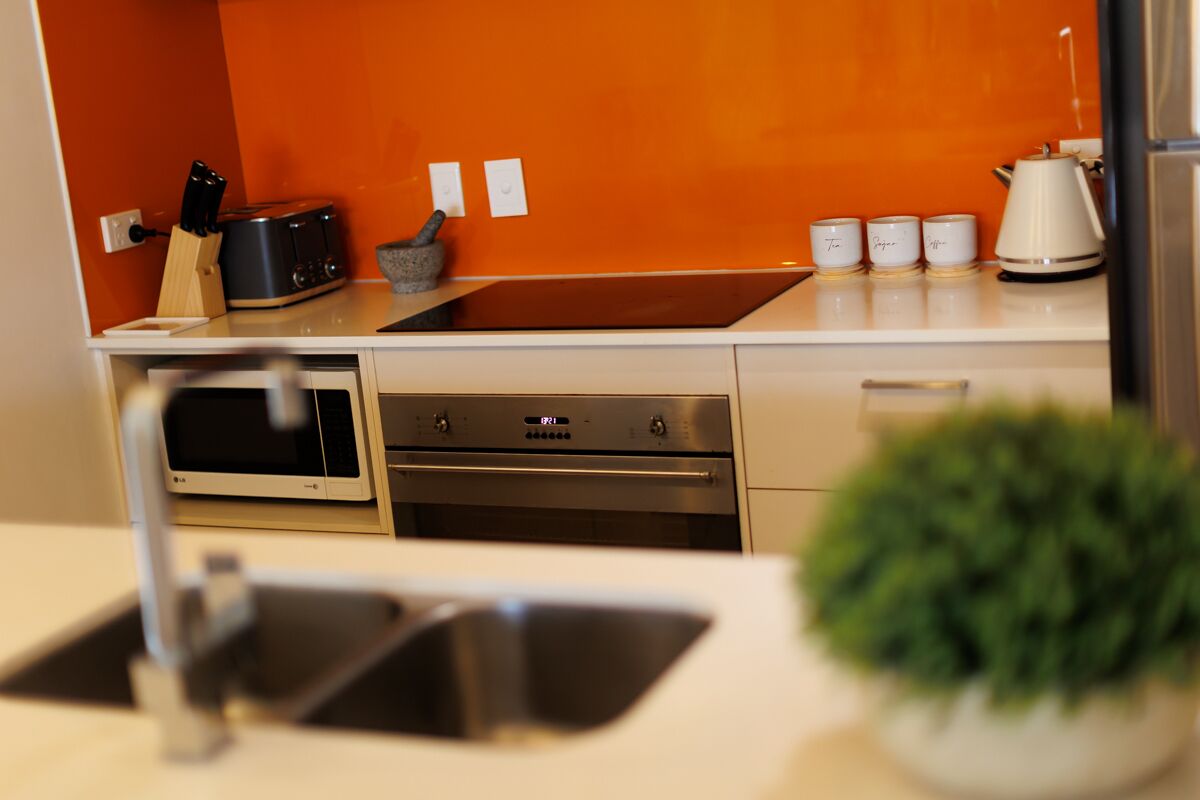 A modern kitchen with a microwave, toaster, and coffee maker on the counter, a sink, and a potted plant.