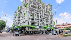 A multi-story building with a modern architectural design, featuring balconies and large windows. - Stylish 3 BR Apartment in The Heart of Darwin CBD with Pool (Darwin City)