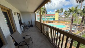 A balcony with a pool view, chairs, and a building in the background.