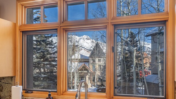A kitchen with a large window overlooking a snowy mountain and a building. - Mountain Village Hideaway 3 Bedroom Townhouse by Alpine Lodging Telluride (Telluride)