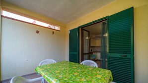 A small dining area with a table covered by a green tablecloth, two white chairs, and a door with green shutters. - APPARTAMENTI BILO SOFI - BILO SOFI CON GIARDINO (Campo nell'Elba)