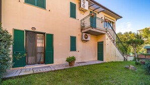 A two-story building with a balcony, a staircase, and a small garden area. - APPARTAMENTI BILO SOFI - BILO SOFI CON GIARDINO (Campo nell'Elba)