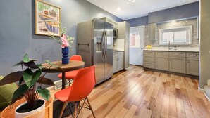 Eine moderne Küche mit Kühlschrank, Holzboden und einer Essecke mit Tisch und Stühlen.