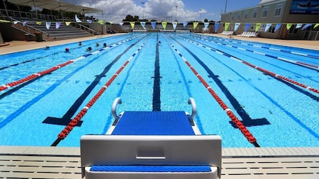 Una piscina techada, una piscina al aire libre, sombrillas