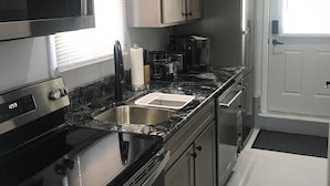 Een moderne keuken met roestvrijstalen apparatuur, een zwart aanrecht en lichtgrijze kastjes.