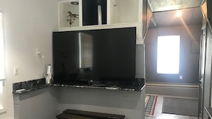 Een kleine keuken met een ingebouwde kookplaat, een bankje en een klein raam.