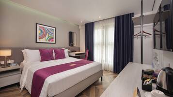 Quarto de hotel moderno com uma cama grande, uma escrivaninha, uma cadeira, um espelho e um guarda-roupa.
