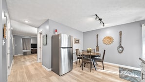 Eine moderne Küche mit einem Edelstahl-Kühlschrank, einem Holzespeisetisch und Stühlen.