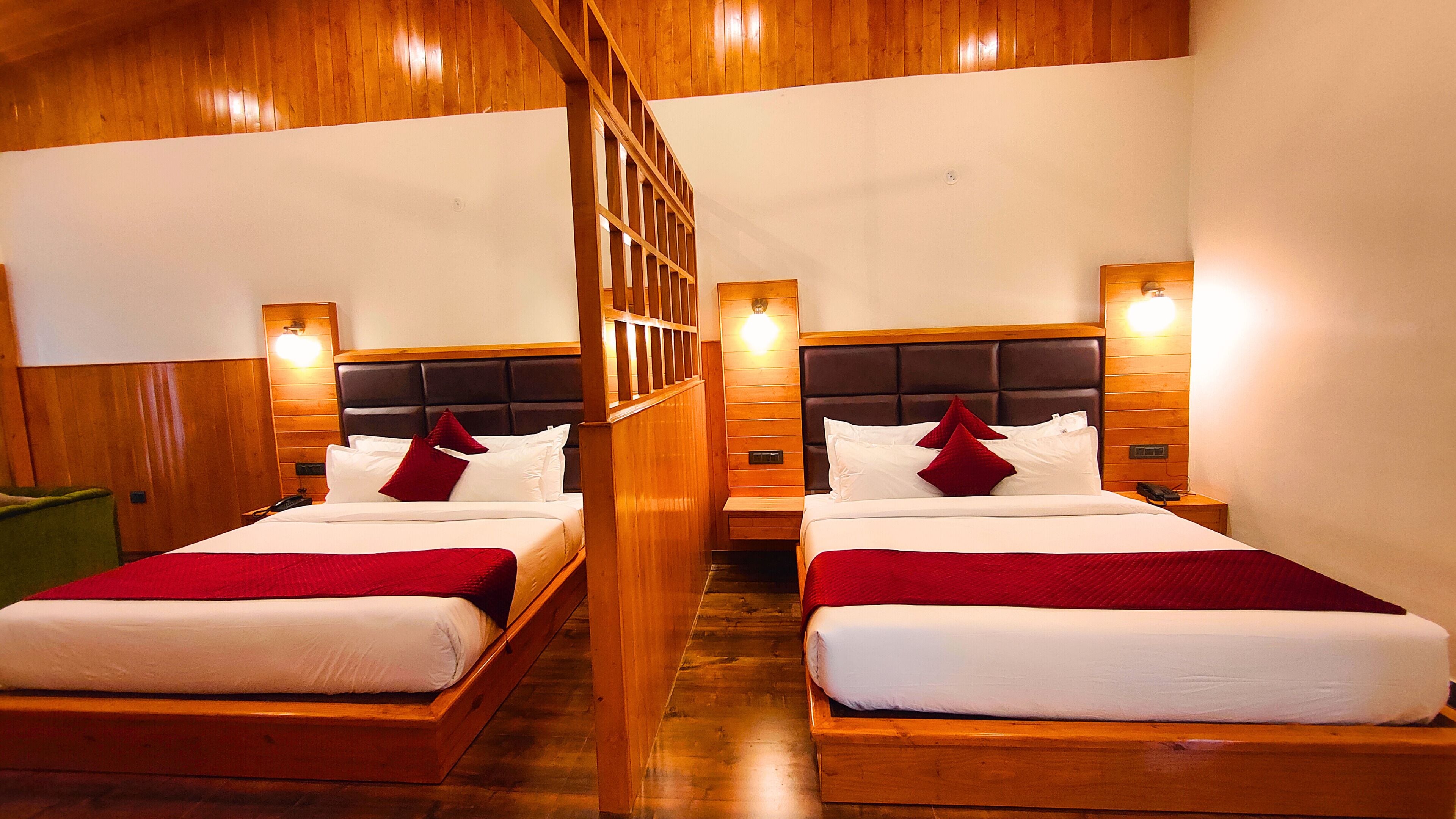 Two wooden beds with headboards, white bedding, and red pillows in a room with wooden walls and floors.