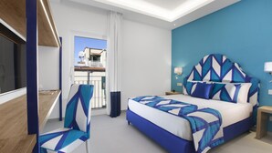 Een moderne hotelkamer met een groot bed, een bureau en een stoel. Een balkon is zichtbaar door het raam.