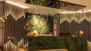 A reception desk with a marble top, vertical wooden slats, and hanging green ornaments. - Kate Hotel Special Class & Spa (Istanbul)