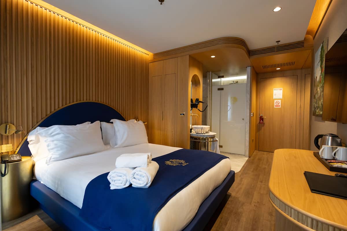 A hotel room with a large bed, a desk, and a bathroom.