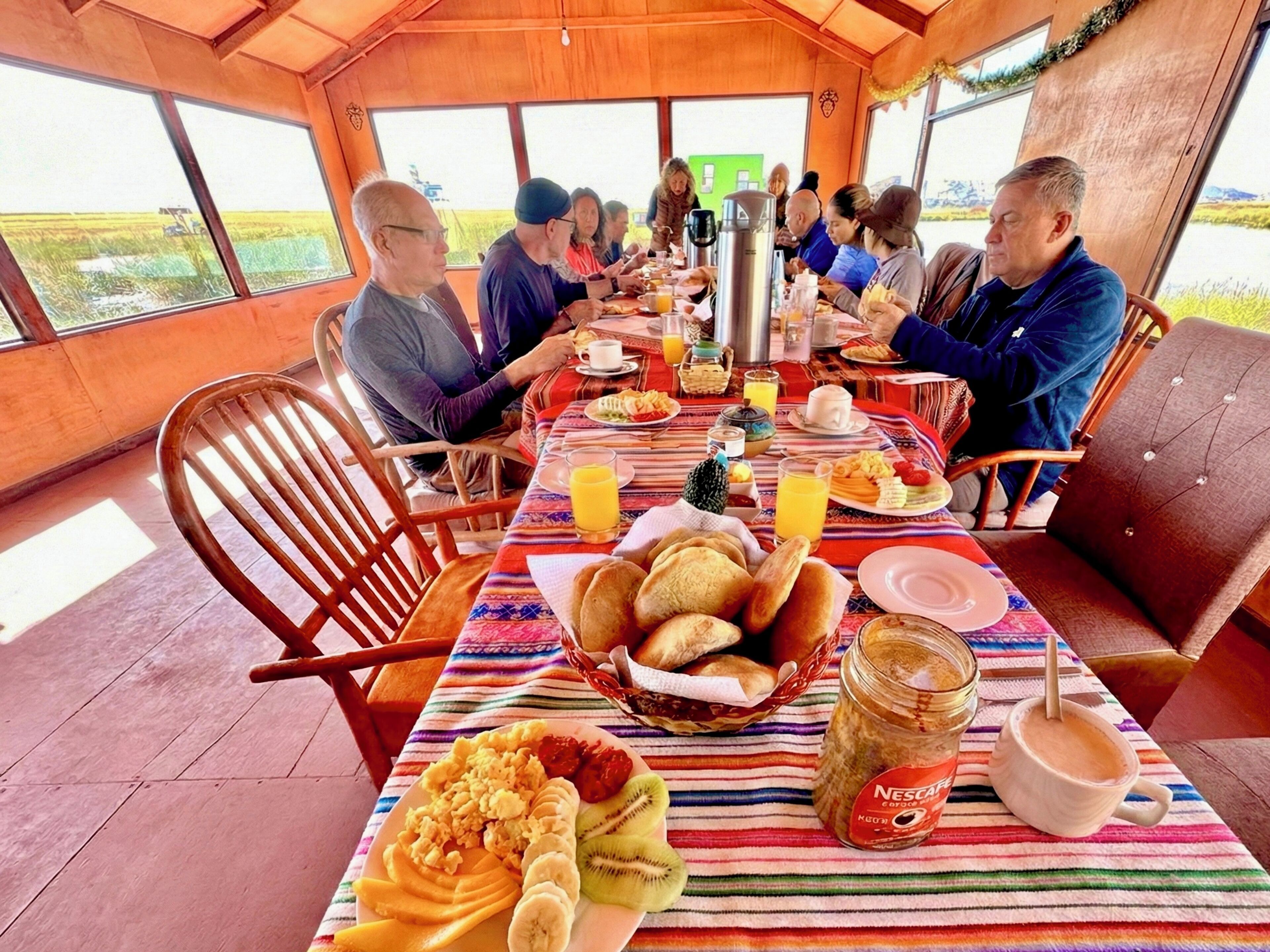 A communal dining area with a long table set for a group meal, featuring a variety of dishes and beverages.
