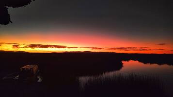 A sunset over a calm body of water with a silhouette of a building on the left.