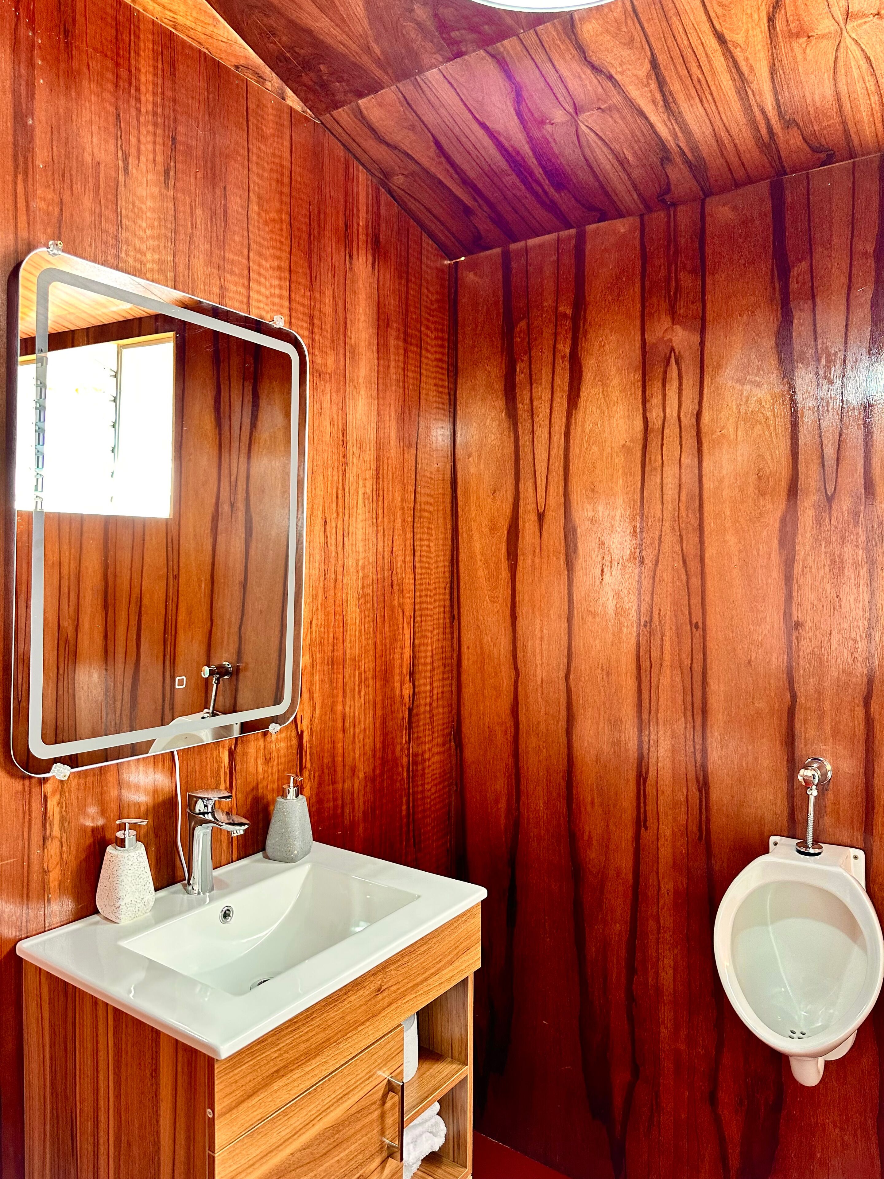 Un bagno con rivestimenti in legno, un lavandino bianco, uno specchio e un bidet.