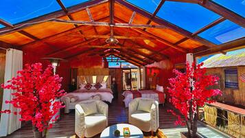 A spacious room with a high ceiling and a wooden structure. There are two white armchairs and a round table with a small decorative item.