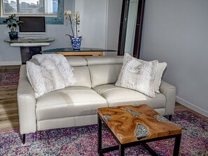 Una sala moderna con un sofá de cuero color beige, una mesa de centro de madera y una alfombra colorida.