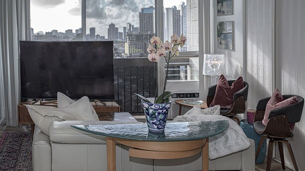 A modern living room with a sofa, a glass coffee table, a TV, and a city view through large windows. - Great Location to the hospitals: 2 bed 1 bath Fully furnished. (Honolulu)
