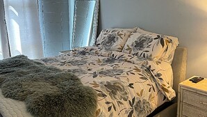 A bedroom with a bed, a nightstand, a mirror, and a window with curtains. - Great Location to the hospitals: 2 bed 1 bath Fully furnished. (Honolulu)