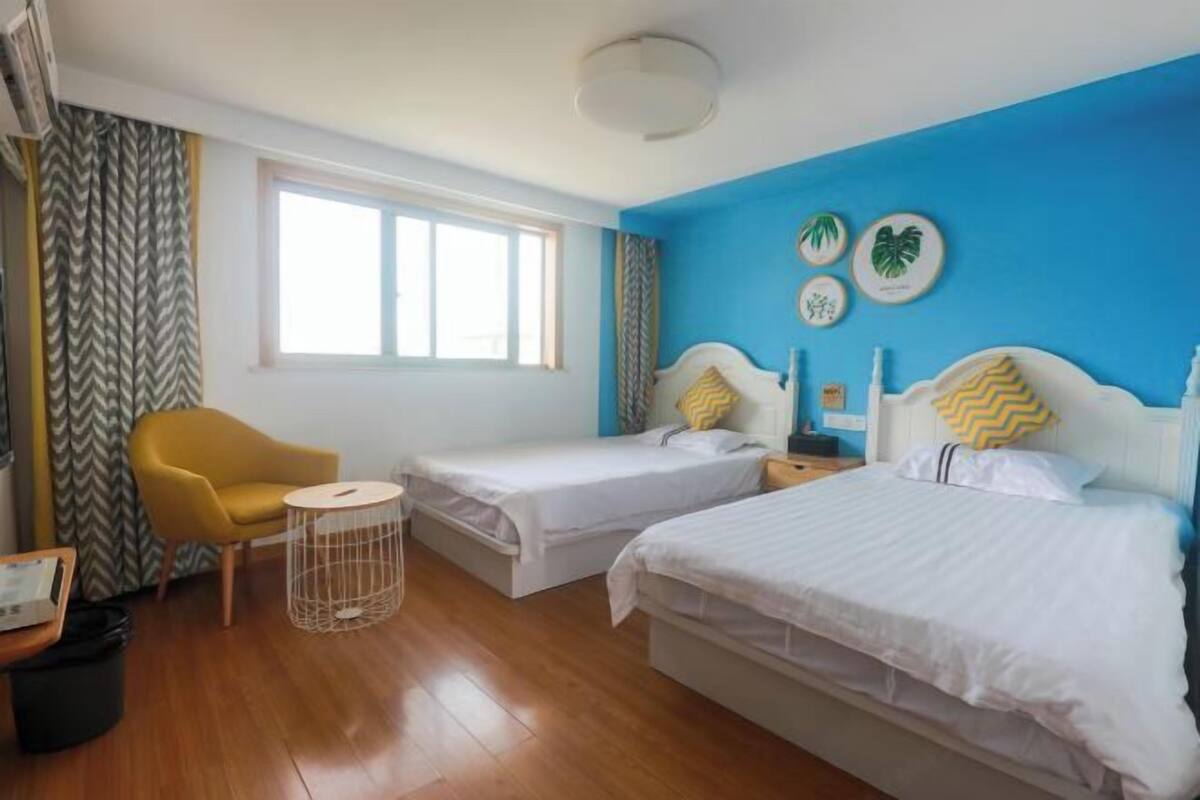 A room with two beds, a chair, a small table, and a window.
