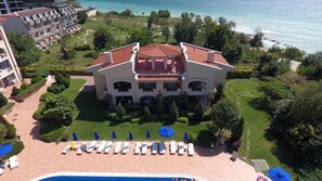 Un grande hotel con un cortile centrale, una piscina e vista sul mare.