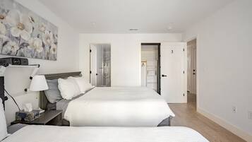 A hotel room with two beds, a nightstand, a lamp, and a painting on the wall.