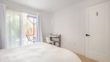 A hotel room with a large bed, a desk, and a chair. There is a door with the number 2 on it.