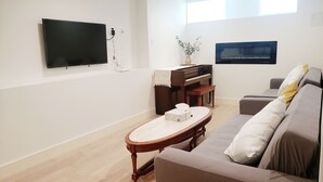Un salon moderne avec un téléviseur à écran plat, un piano, un canapé et une table basse.