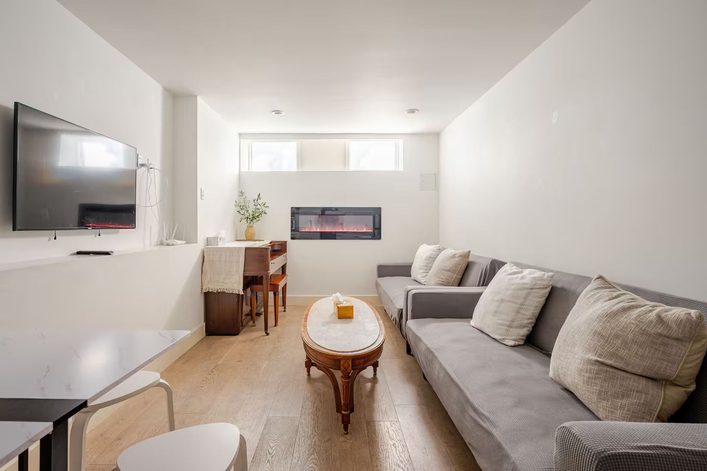 A modern living room with a flat-screen TV, a fireplace, a sofa, and a dining area.