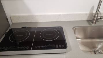 A kitchen with a black induction cooktop and a stainless steel sink.