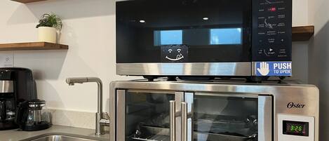 A kitchen with a stainless steel oven, a coffee maker, and a sink.