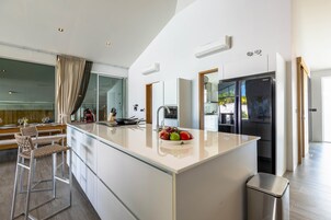 Una cocina moderna con una isla grande, taburetes de bar, un fregadero y un refrigerador.